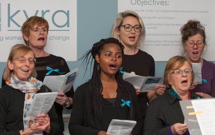 A group of women singing in a choir, for “The Role of Education and Skill-Building at Kyra”