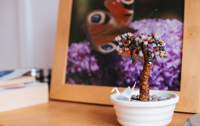 Interior, a small beaded tree sat on a table top with a framed photo in the background, for “Finding Balance and Calm Through Kyra’s Mindfulness Program”