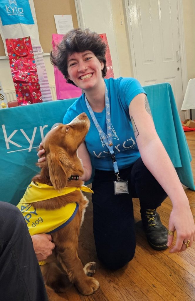 A woman knelt down petting a support dog, for “Meet Lucy and Enya: Kyra’s Four-Legged Support Team”
