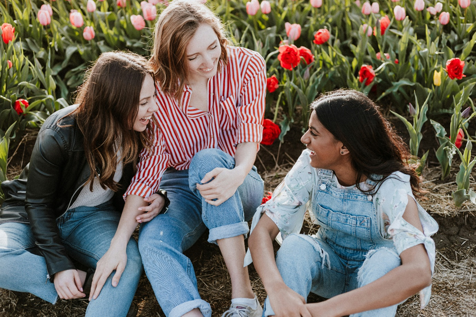 Exterior, three young women sitting in a field full of flowers, for “Introducing ROSE in Focus”
