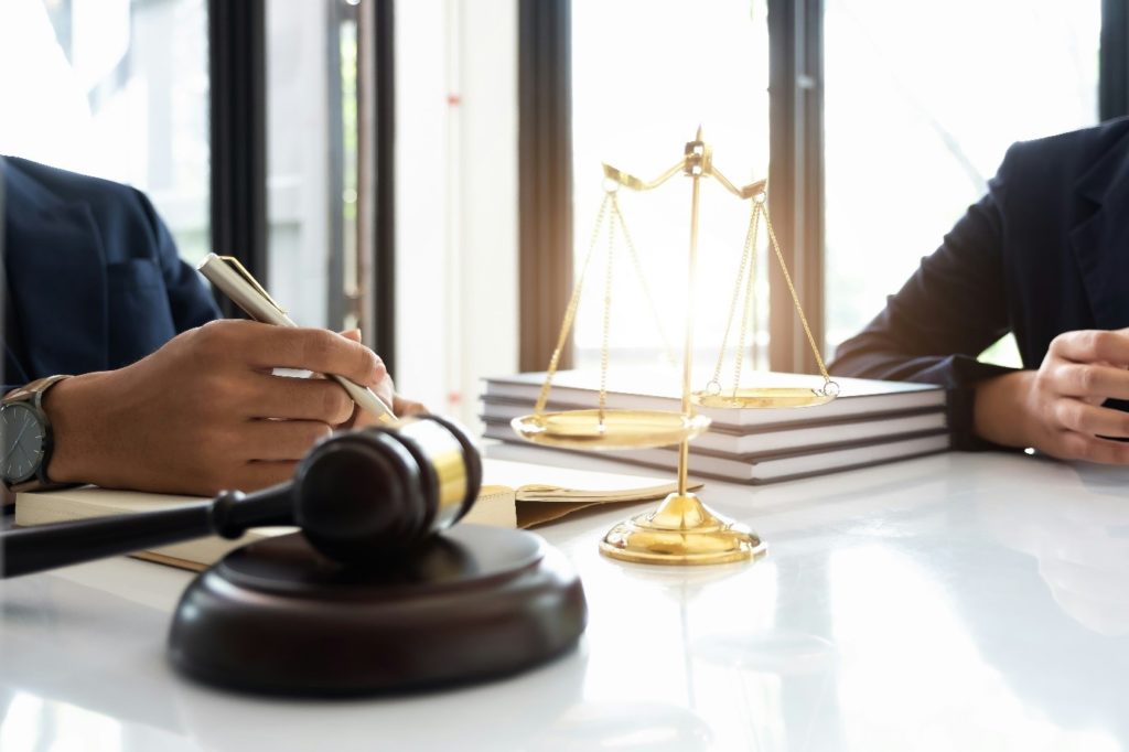 Interior, two people sitting across a table with scales and a gavel, for “Let’s Talk Legal Advice: How Kyra Helps You Understand Your Rights”