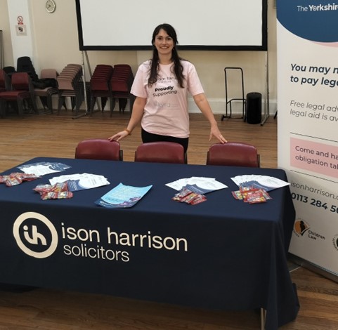 Interior, A woman standing at an Ison Harrison stall with leaflets and posters, for “Let’s Talk Legal Advice: How Kyra Helps You Understand Your Rights”