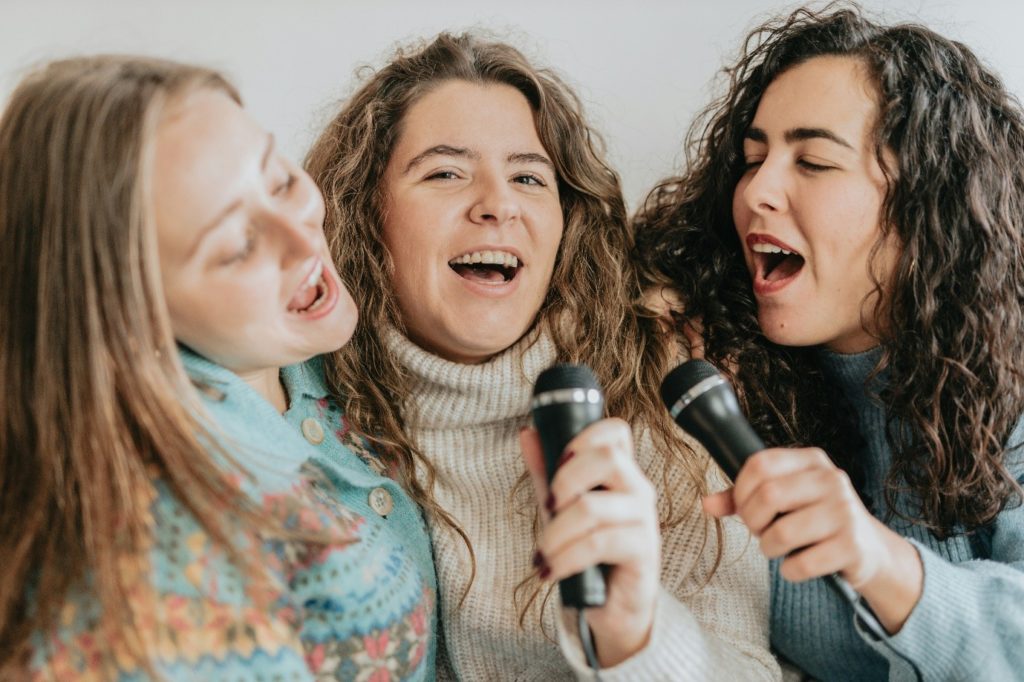 Interior, three women singing into microphones, for “Kyra Voices: Singing for Joy, Connection, and Wellbeing”