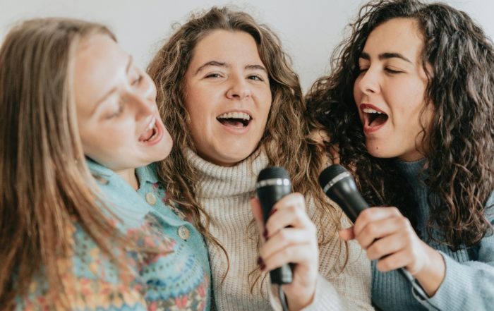 Interior, three women singing into microphones, for “Kyra Voices: Singing for Joy, Connection, and Wellbeing”