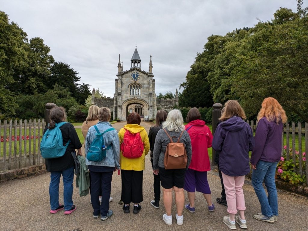 Exterior, several women standing in front of a gothic stone building with their backs turned, for “Taking Steps Toward Better Wellbeing”