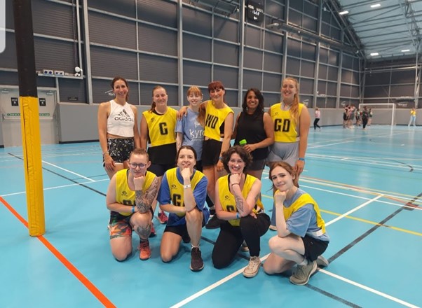 Interior, a women’s netball in a sports centre smiling at the camera, for “A Huge Thank You to AVIVA for Supporting Kyra Through Sport”
