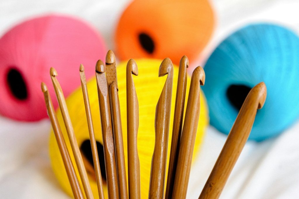 Interior, several crochet hooks in front of some vibrant, multi coloured wool, for “Celebrating Member’s Week at Kyra”