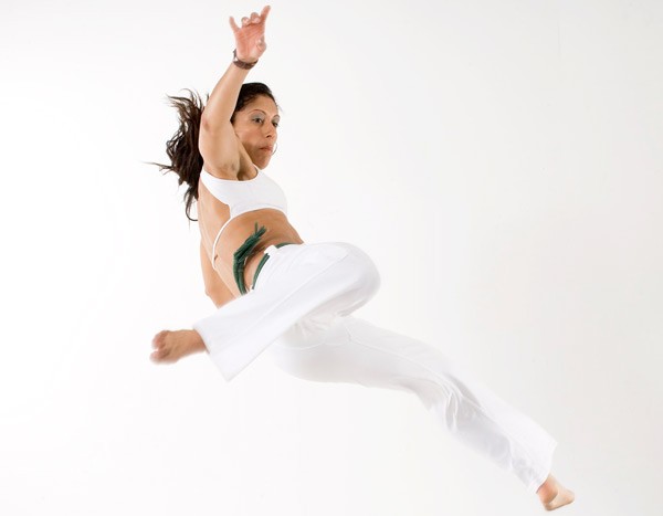 Interior, a women mid flip during a capoeira dance, for “Finding Strength in Movement: Capoeira Comes to Kyra”