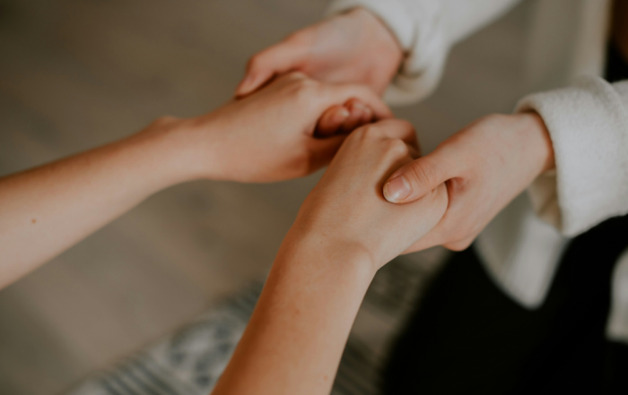 Interior, two women supportively clasping each other’s hands, for “New Monthly Workshop: Exploring the Five Ways to Wellbeing"