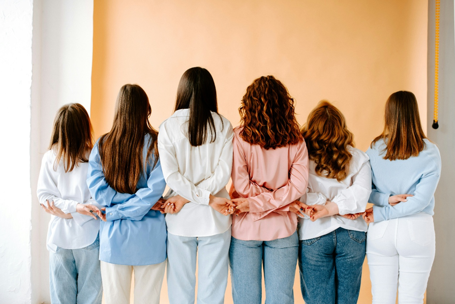 Interior, a line of women with their back to the camera holding hands, for “From Surviving to Reclaiming: A FREYA Journey”
